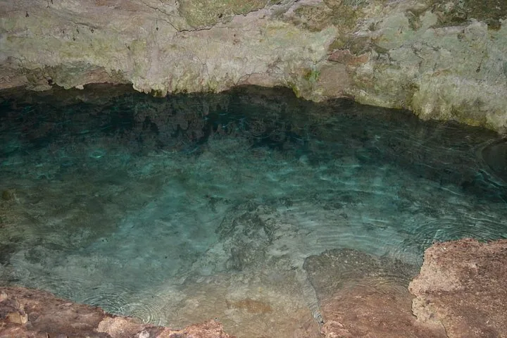 Ein Becken mit klarem, flachem blauem Wasser in einer Felshöhle.