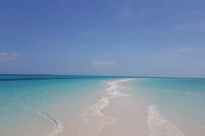 Eine makellose weiße Sandbank, die sich unter klarem blauem Himmel in türkisfarbenes Wasser erstreckt.